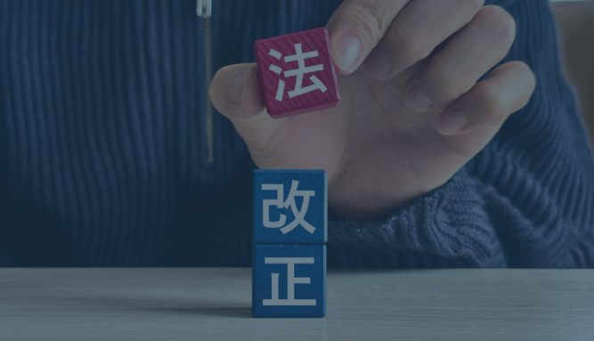 「法」「改正」と書かれた積み木とスマートフォンで本人確認するイメージ